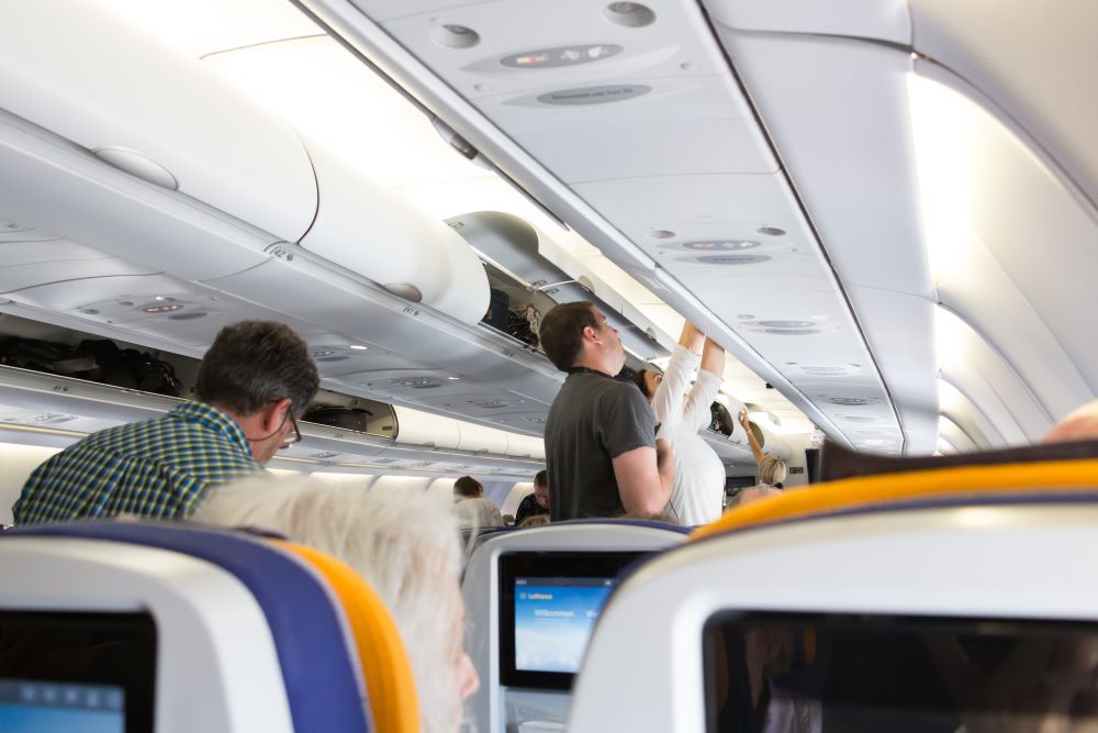 Passagiere verstauen ihr Handgepäck im Flugzeug von Lufthansa