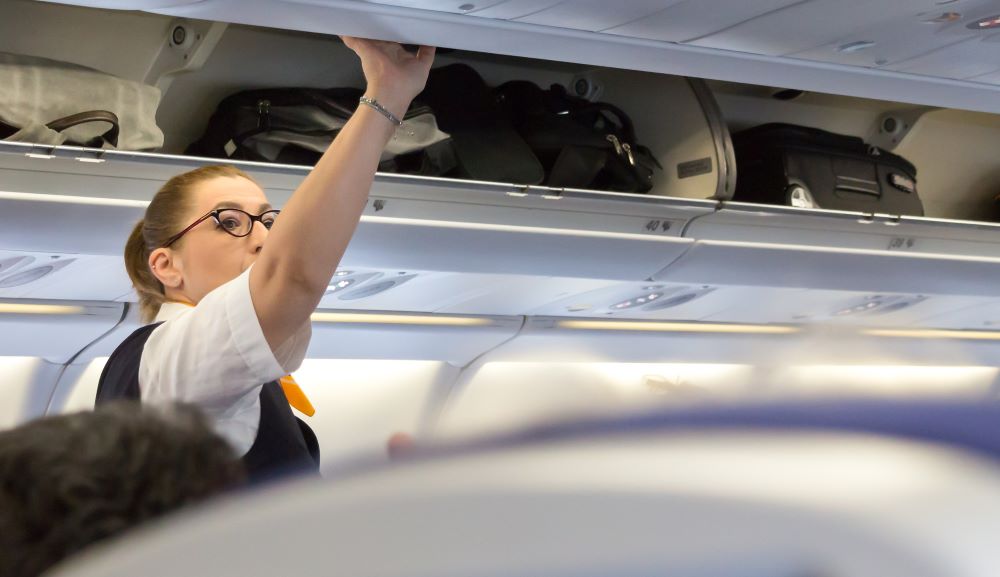 Stewardess überprüft Handgepäck Fächer im Lufthansa Flieger